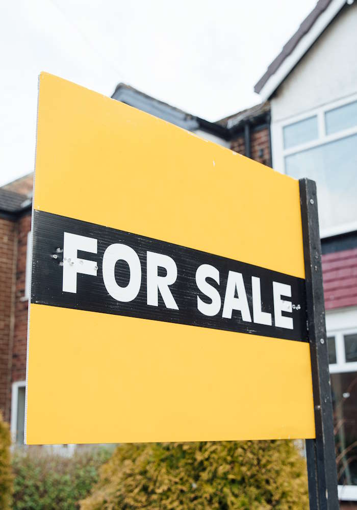A for-sale sign in front of a residential house